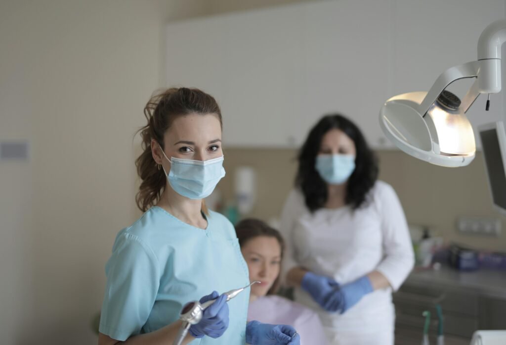 Dental professionals in protective gear attending to a patient in a clinical setting.