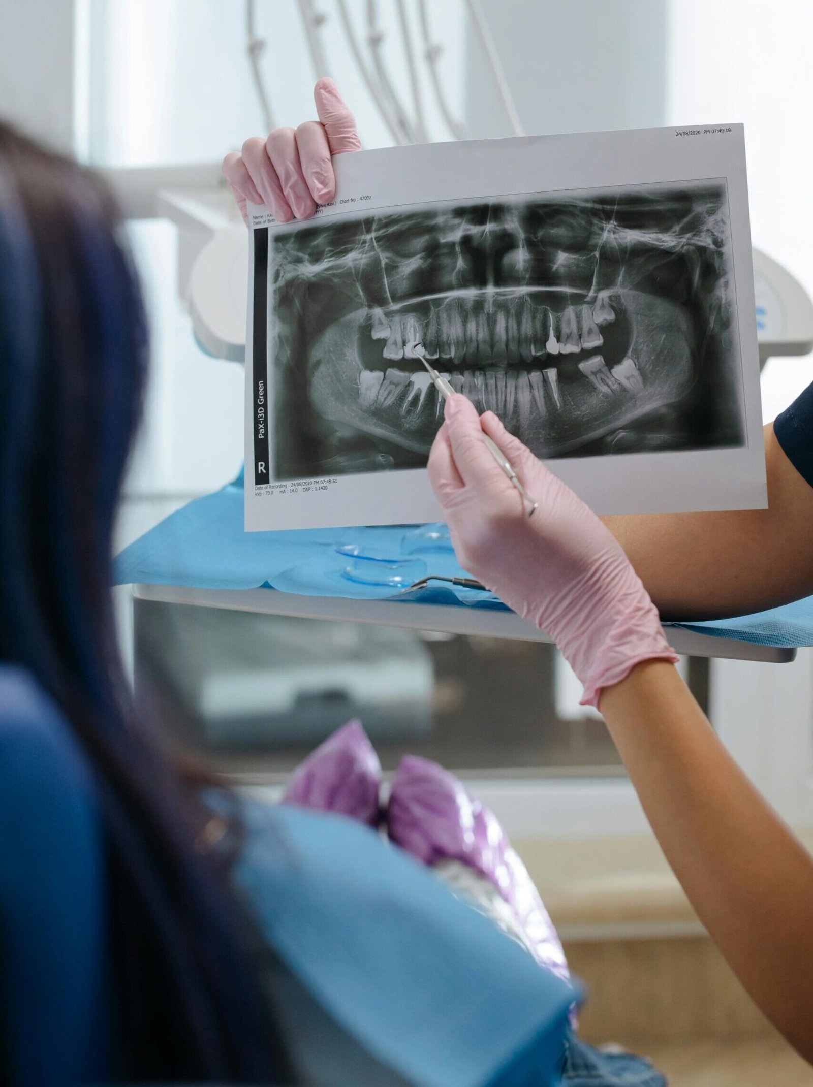 A dentist showing a dental X-ray to a patient in a clinic setting.