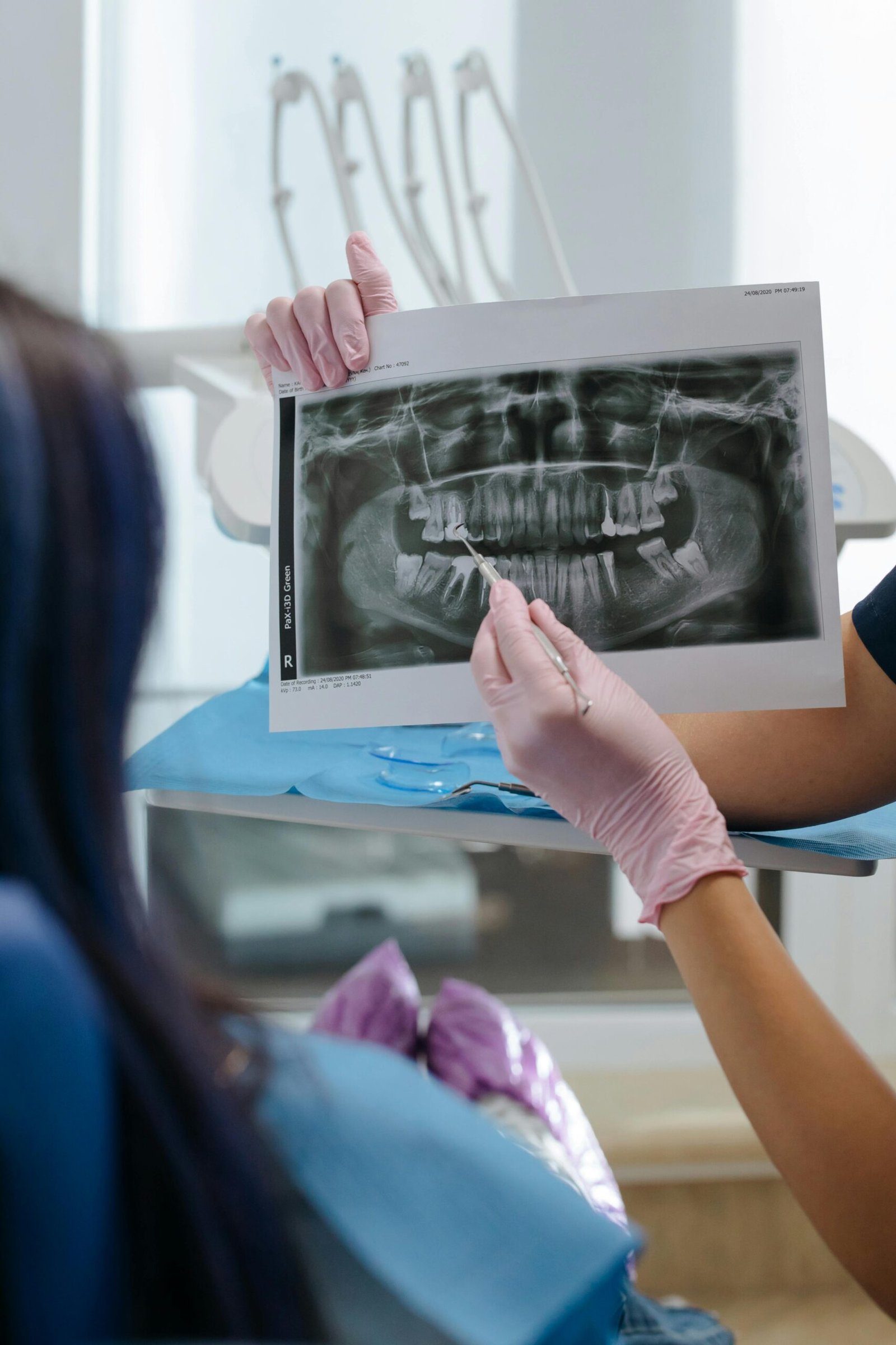 A dentist showing a dental X-ray to a patient in a clinic setting.