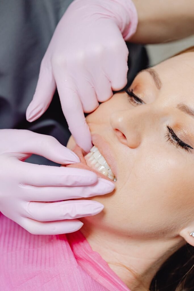 A dentist wearing gloves examines a patient's teeth in a close-up view during a dental check-up.